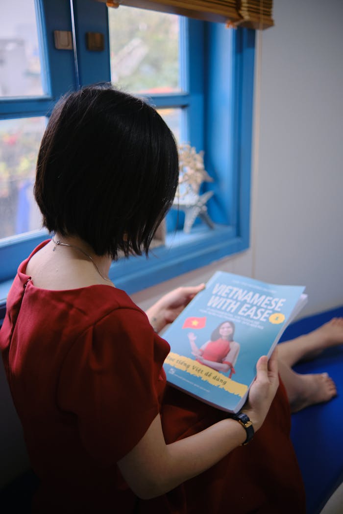 A woman sits by a window reading Vietnamese with Ease.
